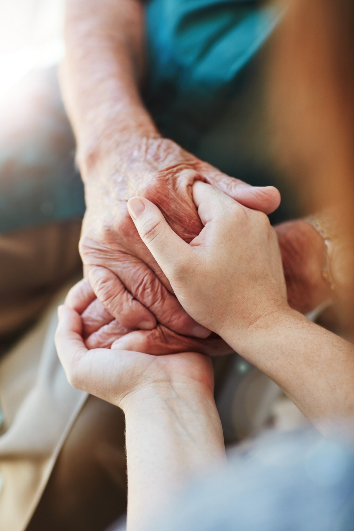 A woman holding a senior man's hands in comfort