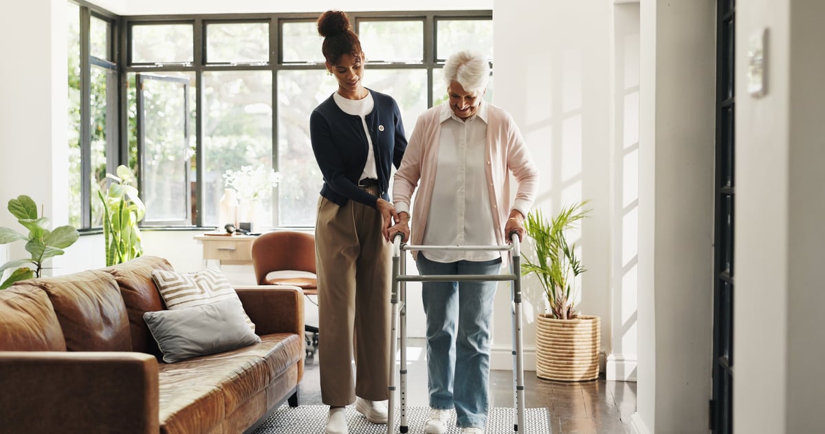 Caregiver helping elderly patient with a walker
